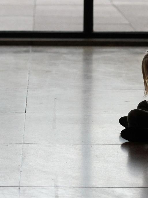 Mädchen sitzt in der Schule auf dem Boden