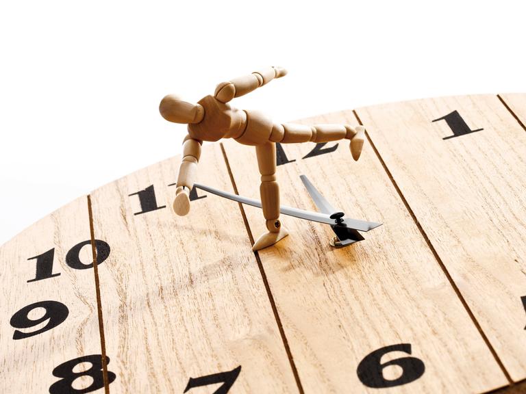 Gliederpuppe auf Uhr, Symbol "die Zeit rennt"