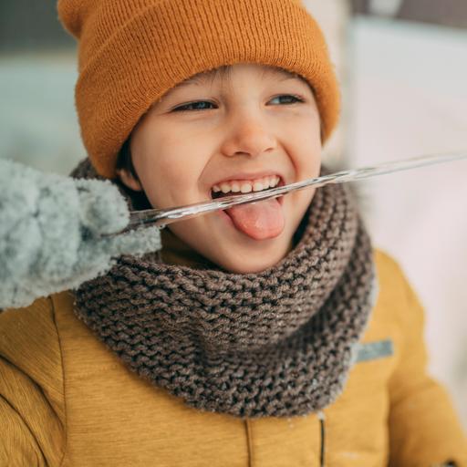 Junge im Winter leckt  an einem Eiszapfen